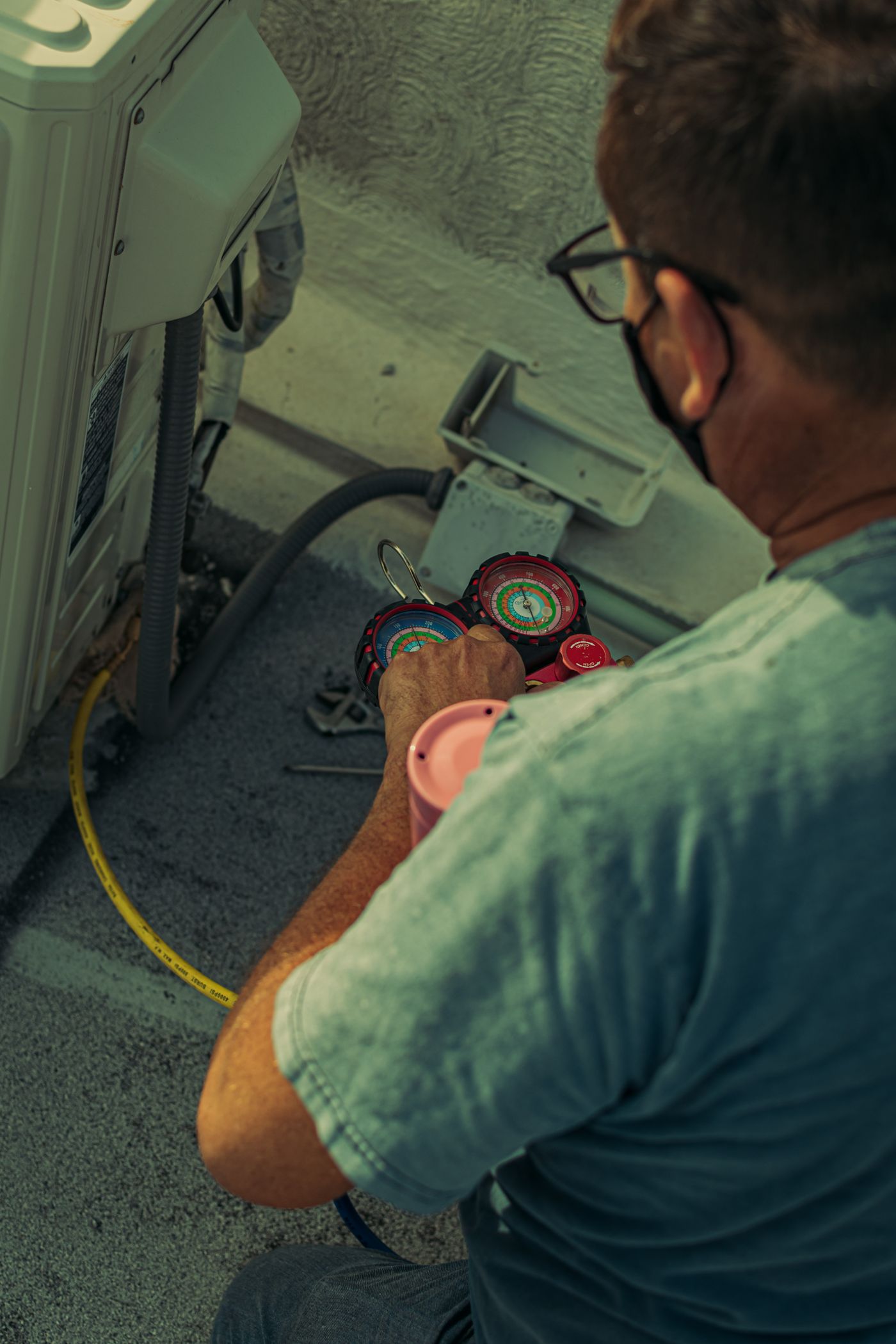 HVAC technician checking refrigerant pressures on an AC unit